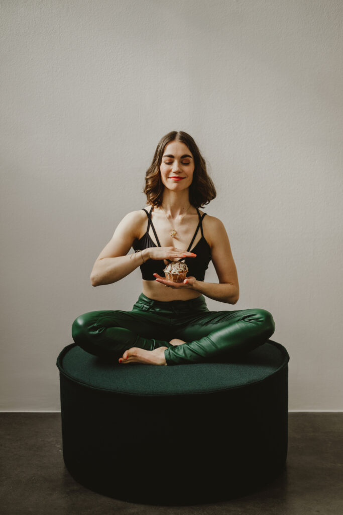 Lisa im Yogasitz und balanciert einen Muffin
